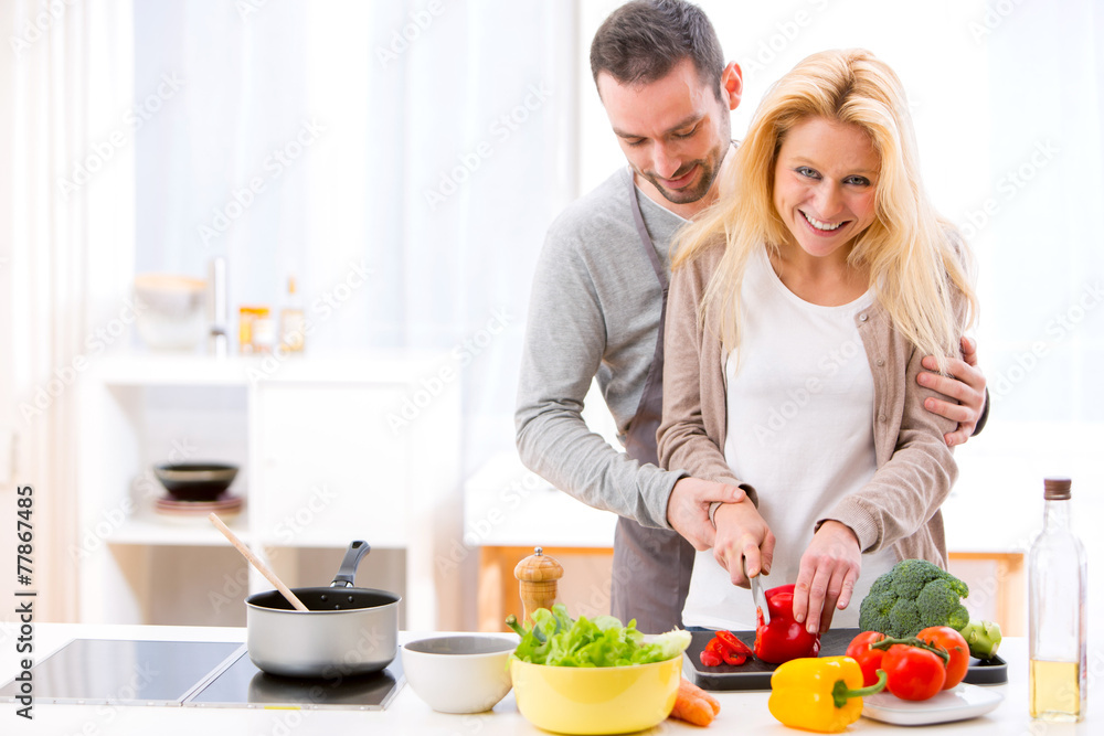 Young attractive man helping out his wife while cooking