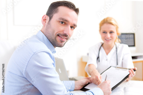 Patient signing the document of a young attractive doctor