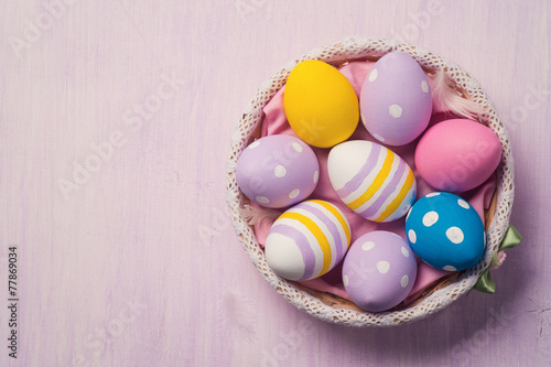 Colorful Easter eggs in a basket, with space for text. Top view