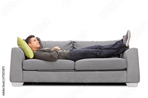 Pensive young guy laying on a sofa