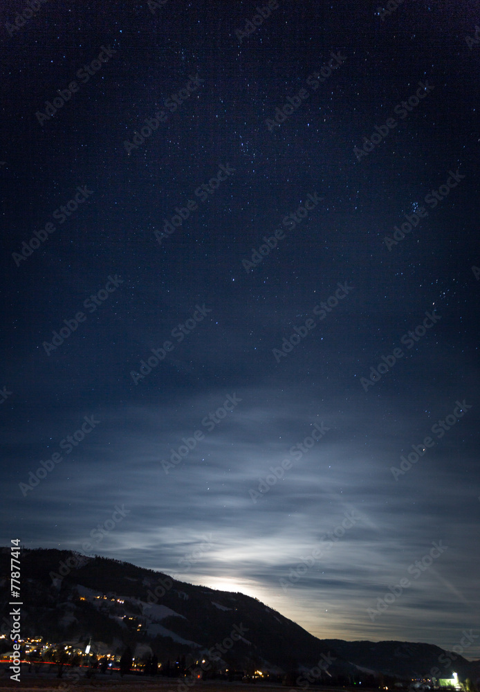 mountain silhouette against starry nigh sky and shining moon