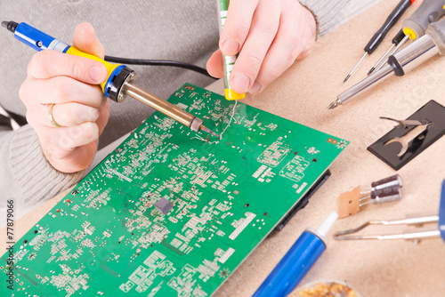 Serviceman soldering on PCB