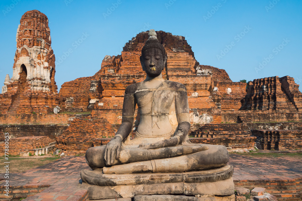 The Buddha statue with old dilapidated temple in background The Buddha statue with old dilapidated temple in background