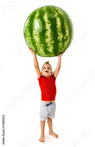 strong little boy lifting a big watermelon