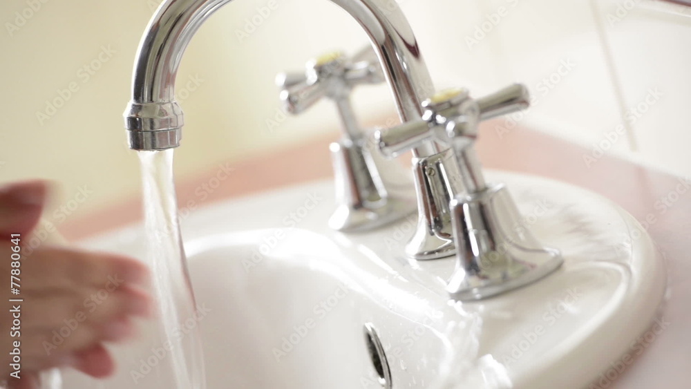 Washing hands thoroughly under running water in bathroom sink with a bar of soap to fight disease such as the COVID-19 novel coronavirus pandemic Washing hands thoroughly under running water in bathroom sink with a bar of soap to fight disease such as the COVID-19 novel coronavirus pandemic
