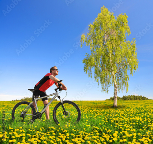 Biker with the mountain bike in the dandelion field