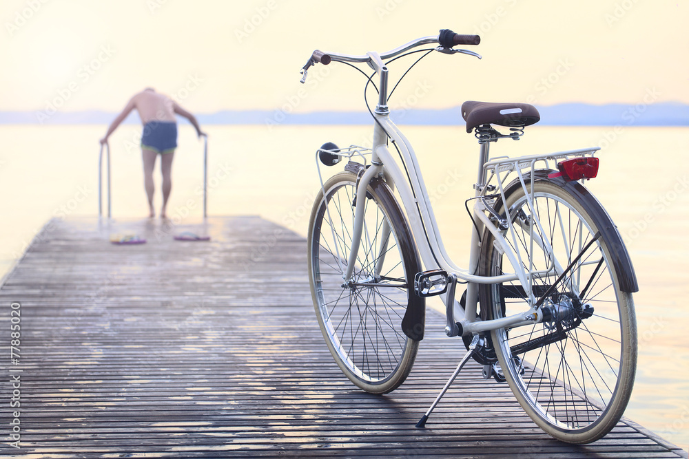 man parks bike on boardwalk befor jumping into the water