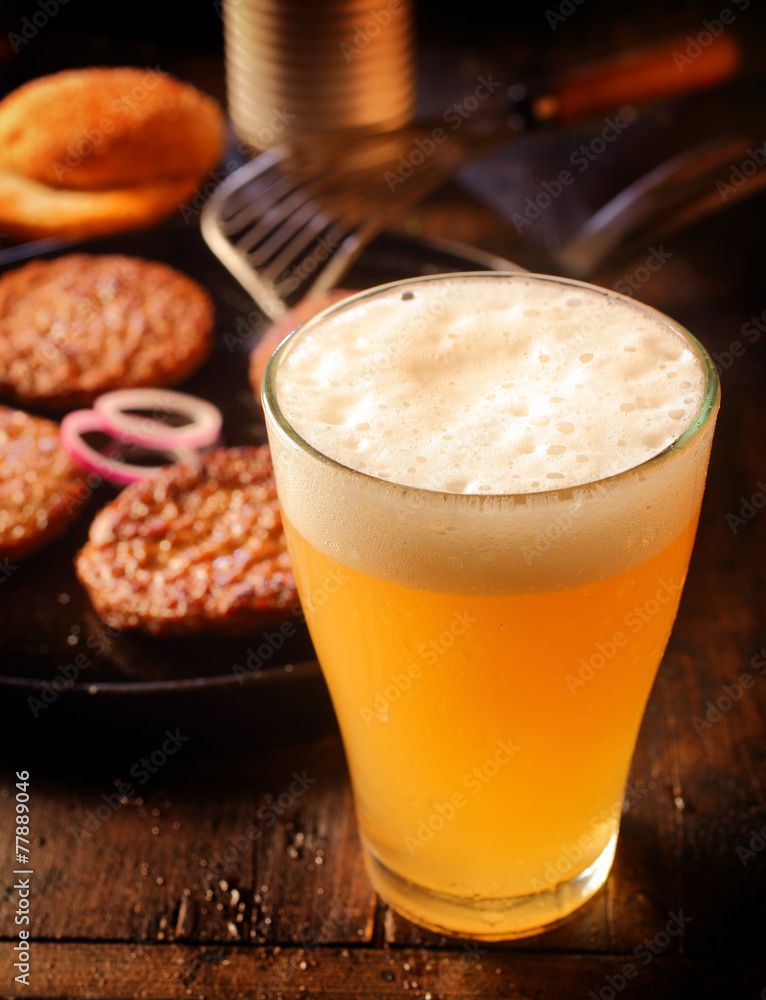 Cold glass of frothy beer with burger patties