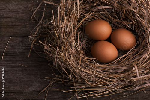 chicken organic eggs with straw in nest on burlap background