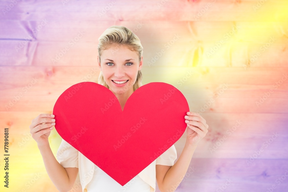 Composite image of attractive young blonde showing red heart Composite image of attractive young blonde showing red heart