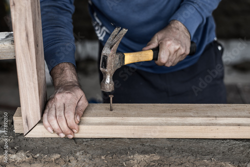 Fototapeta Builder's hands hammering nail into wood