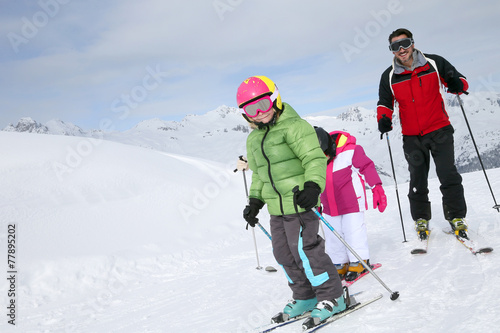 Family skiing down ski slope in winter
