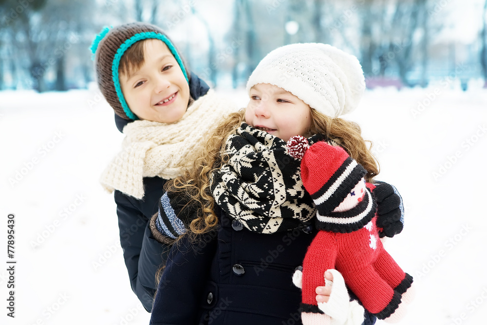 Small children boy and girl play together in a snowy winter park