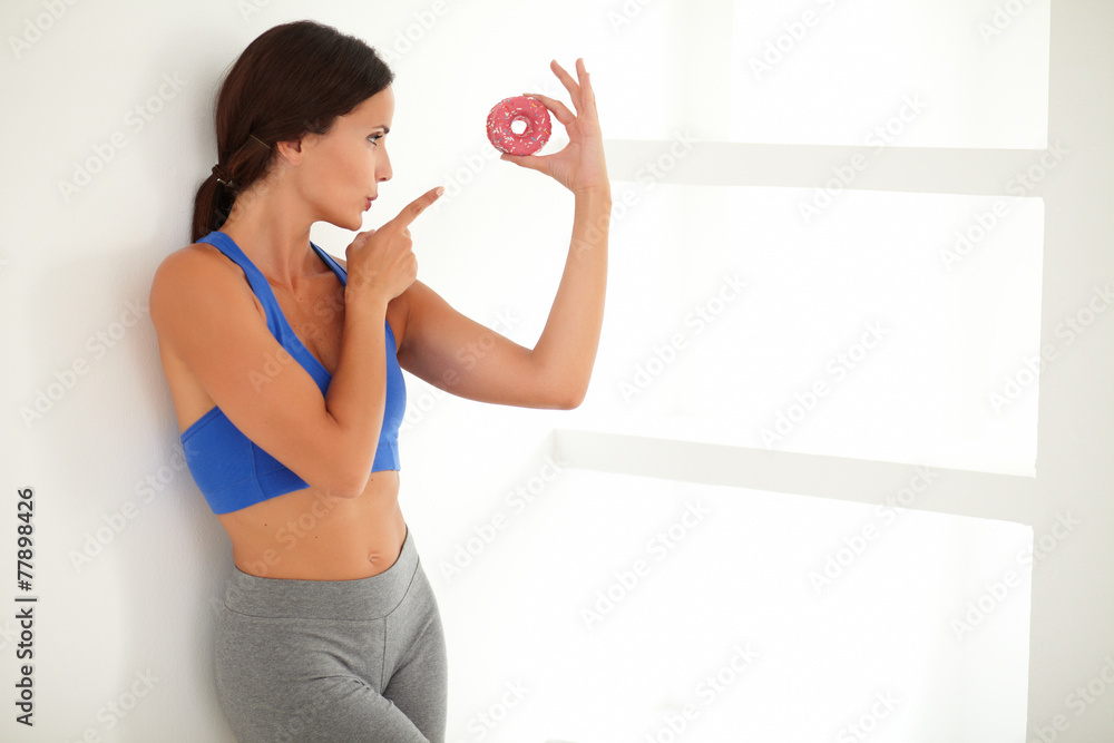 Hispanic brunette standing and pointing at donut Hispanic brunette standing and pointing at donut