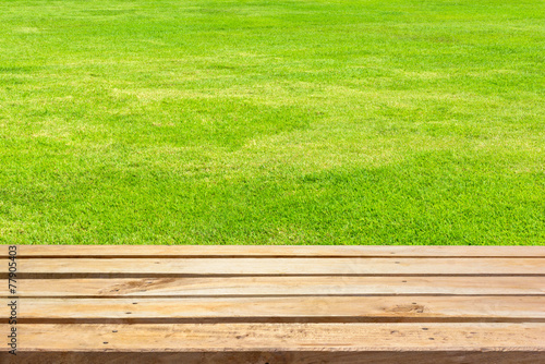 Empty wooden deck table on green grass background