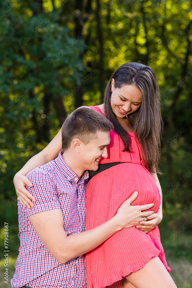 Fototapeta premium Happy and young pregnant couple hugging in nature