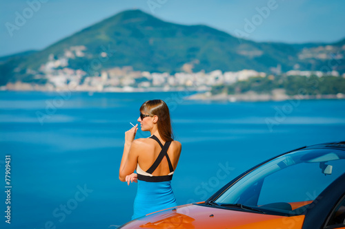 Beautiful young woman sitting on orange cabriolet