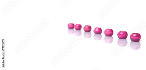 Pink round wooden beads over white background