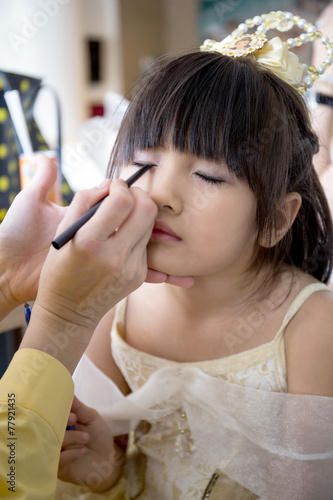 professional makeup artist working with cute asian child