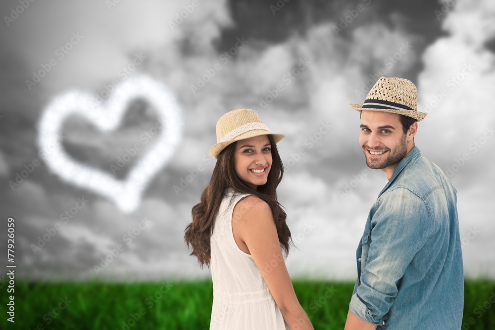 Fototapeta premium Happy hipster couple holding hands and smiling at camera