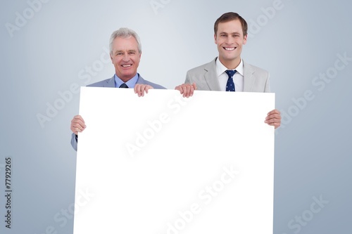 Composite image of smiling tradesmen holding blank sign
