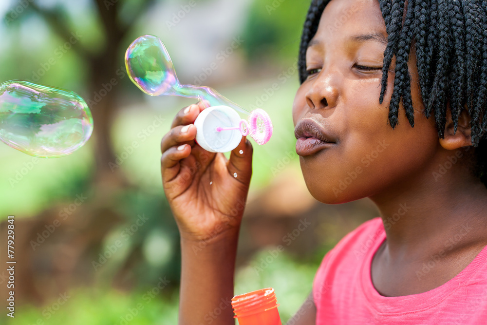 African girl with braids blowing bubbles.