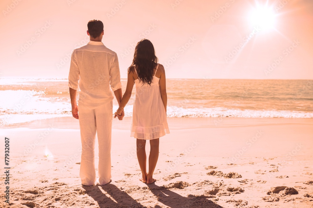 Attractive couple holding hands and watching the waves