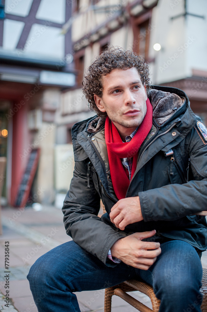 Junger Mann sitzend auf einer Bank Urbano Locken City