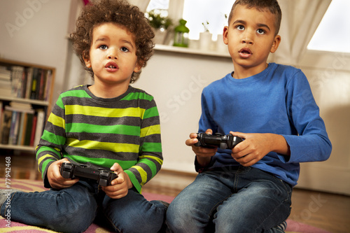 Mixed race boys playing video games at home.