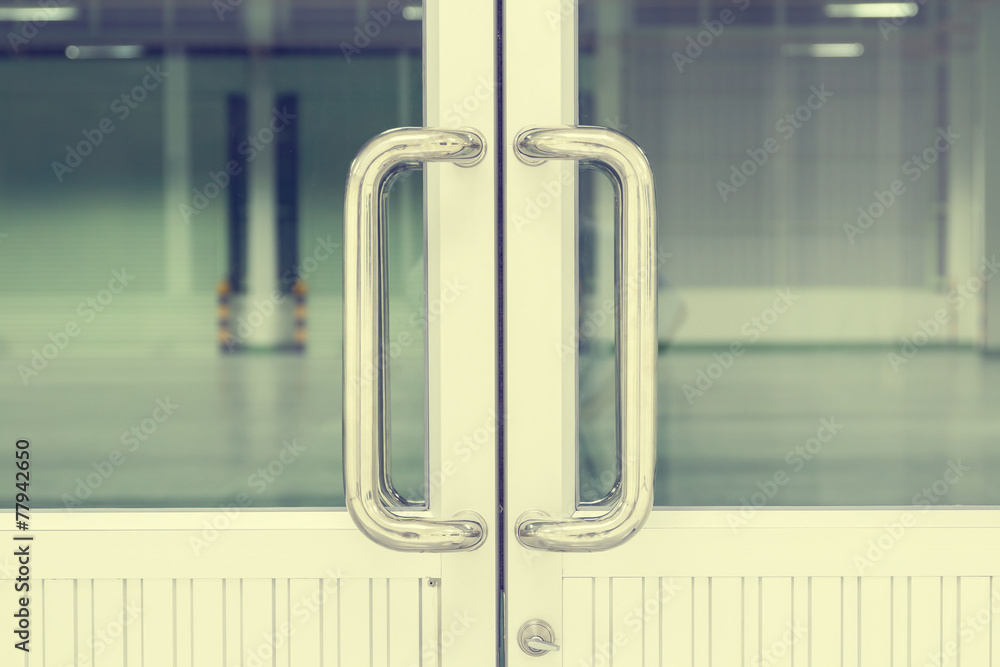 Naklejka premium Door handle part of aluminium door at interior office, factory. Modern style design with long metal steel rod, chrome or stainless steel for access room by holding, pull, sliding, open or close door.