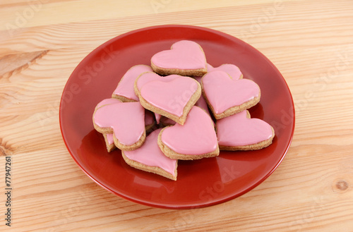 Red plate stacked high with iced heart-shaped cookies