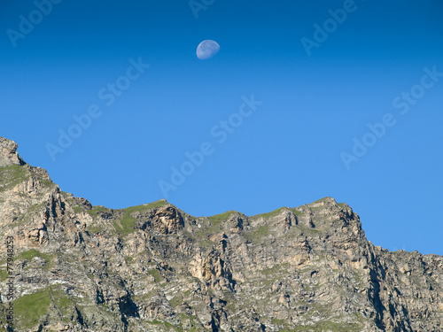 Moonrise over a ridge in the austrian Alps with a clear blue sky