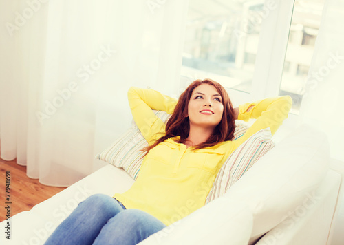 smiling young woman lying on sofa at home © Syda Productions