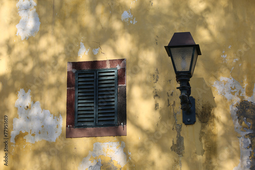 Yellow wall with window shutter and lamp
