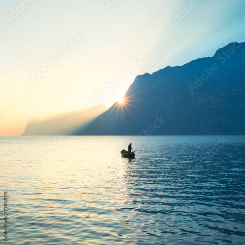 fisherman fishing in the lake under amazing sunset
