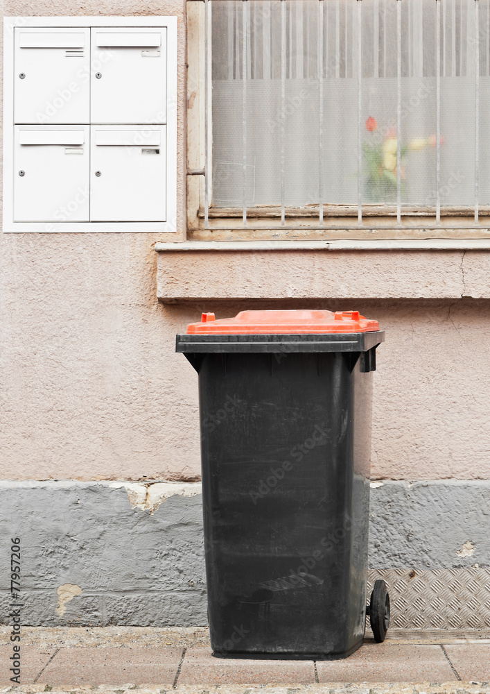 Eine schwarze Mülltonne mit rotem Deckel Stock-Foto | Adobe Stock