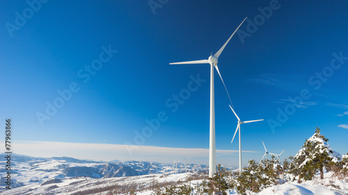 Typical windmill or aerogenerator of aeolian energy on snowy lan photo