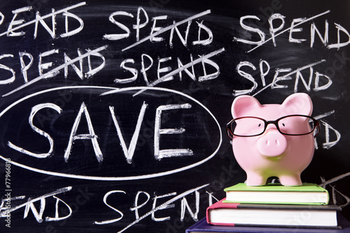 Piggy Bank piggybank wearing glasses with spend savings plan message written on a blackboard or chalk board photo