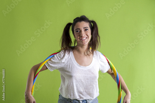 beautiful young woman with colored hula hoop isolated on green b photo