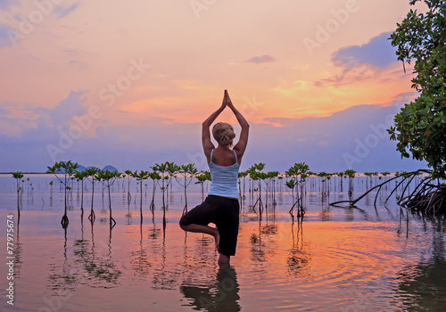 Woman practicing yoga on the beach near  mangroves