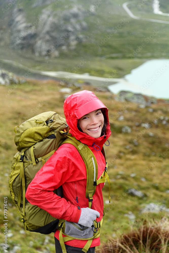 Hiker woman hiking with backpack in rain on trek