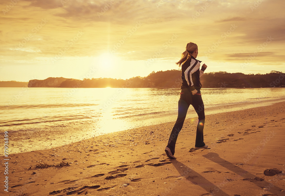 Healthy woman running on the beach at sunset