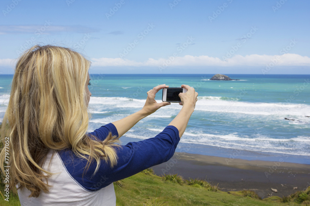 Woman taking a photo at the beach with her smartphone