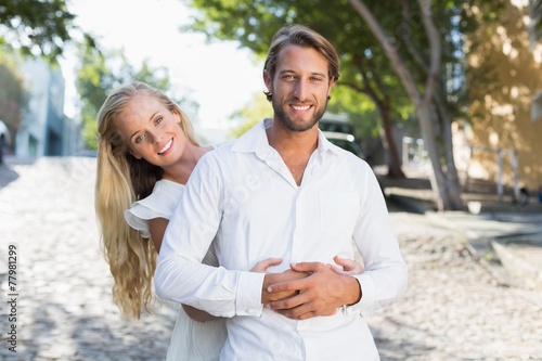 Attractive couple hugging each other and smiling at camera