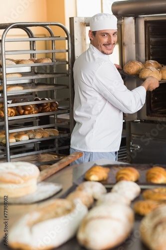 Happy baker taking out fresh loaves