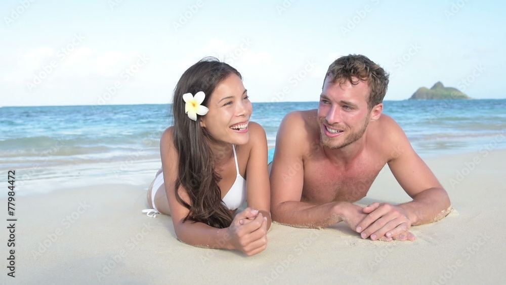 Vacation couple laughing relaxing on beach tanning Vacation couple laughing relaxing on beach tanning