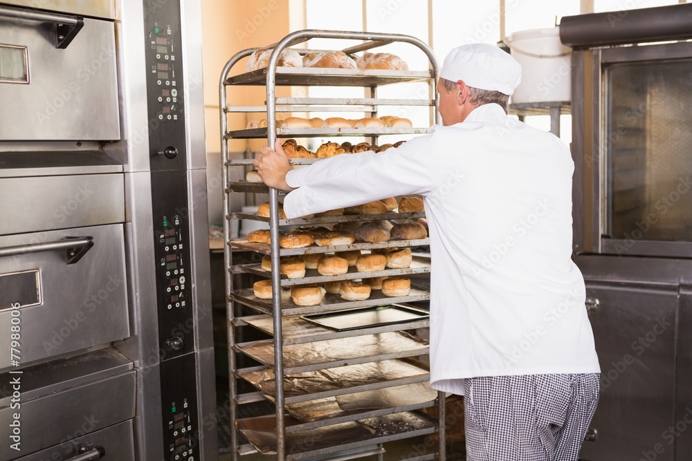 Smiling baker pushing tray of bread Smiling baker pushing tray of bread