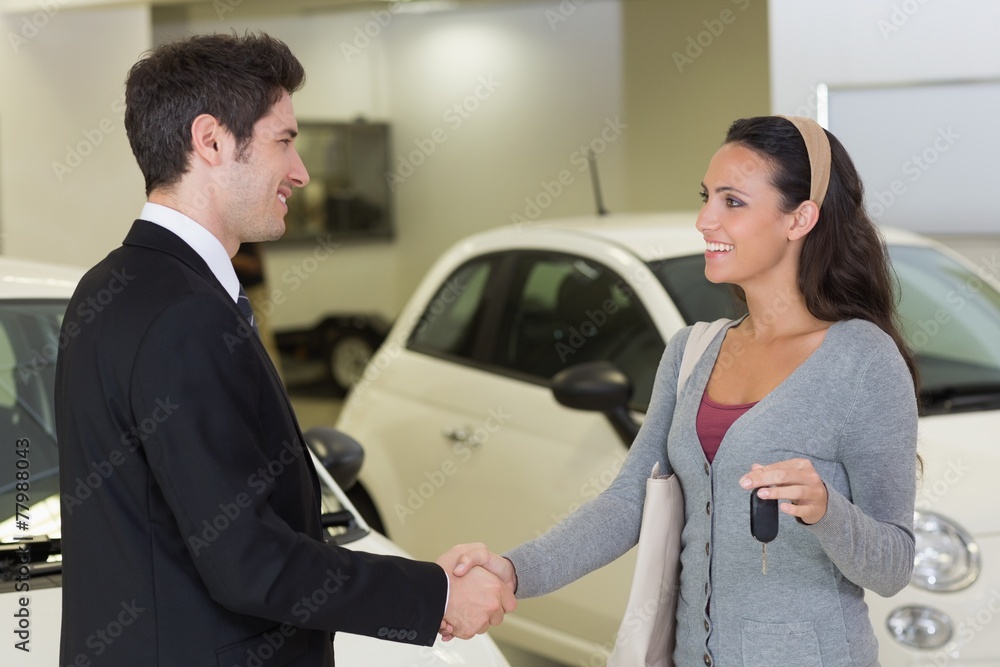 Businessman giving car key while shaking a customer hand Businessman giving car key while shaking a customer hand