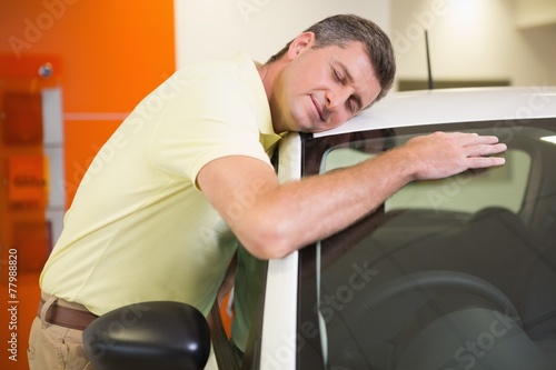 Smiling man hugging a white car