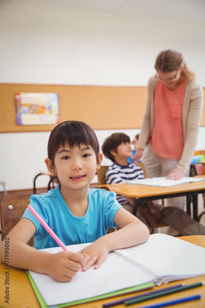 Cute pupils writing at desk in classroom Cute pupils writing at desk in classroom